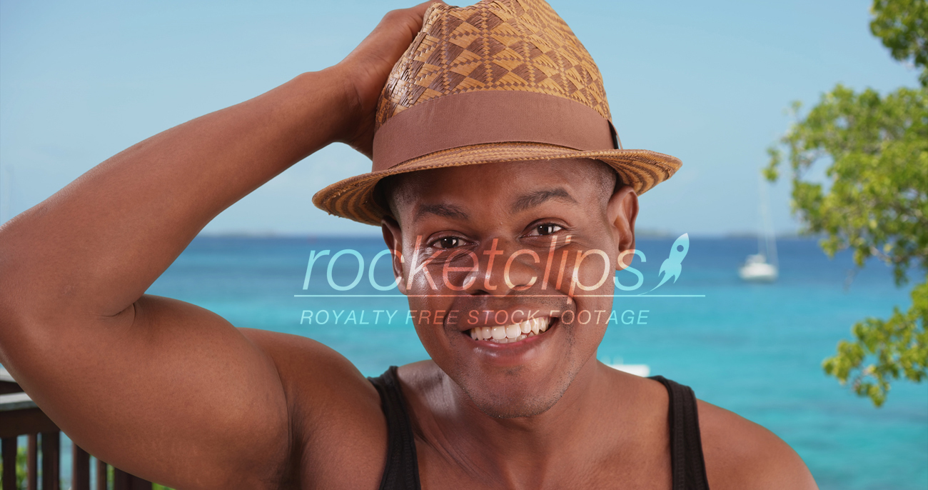 Black man poses happily for a portrait by the beach