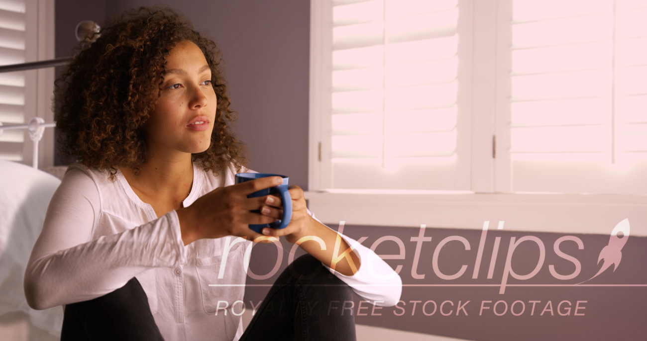 Attractive young black woman thinking and drinking from coffee cup.