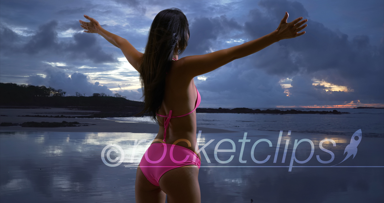 White millennial female looks out onto the stormy sunset on the beaches of St John