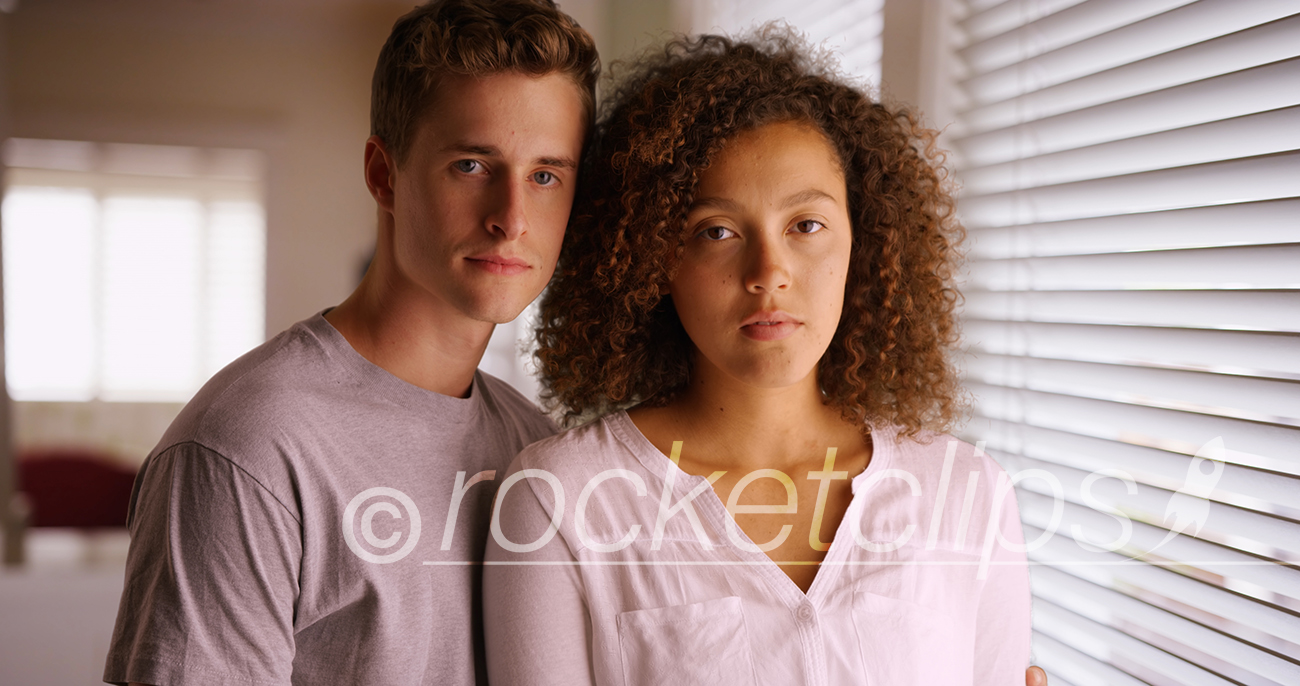 Unhappy couple looking into camera indoors