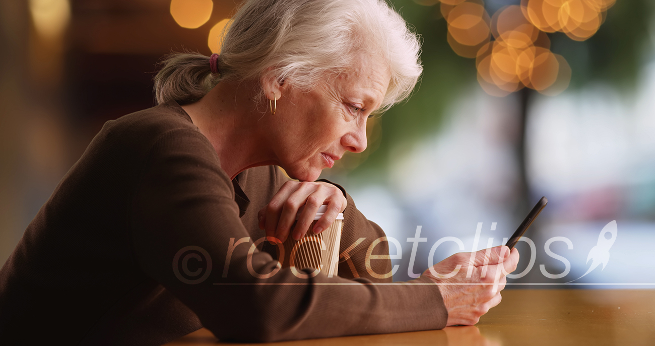 Side portrait of old woman reading concerning text on smartphone at cafe