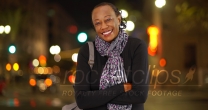 A portrait of an older African American woman laughing in the cold weather on a busy street corner