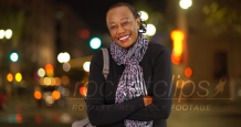A portrait of an older African American woman laughing in the cold weather on a busy street corner
