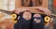 Young white female wearing ripped jeans and a tank top sitting outside building