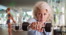Fit elderly lady at gym working out and looking at camera with determination