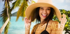 Young white girl in a sun hat poses for a portrait on a Caribbean beach