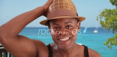 Black man poses happily for a portrait by the beach