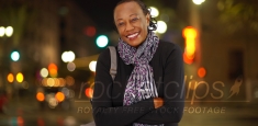 A portrait of an older African American woman laughing in the cold weather on a busy street corner