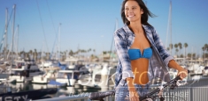 Young Caucasian girl rides her bike next to the marina
