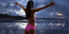 White millennial female looks out onto the stormy sunset on the beaches of St John