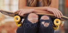 Young white female wearing ripped jeans and a tank top sitting outside building