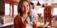 Woman drinking coffee or tea from mug inside contemporary kitchen