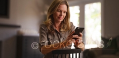Caucasian woman messaging on smartphone seated in chair in living room