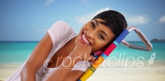 Young black female sitting by the ocean on Caribbean beach talking to camera
