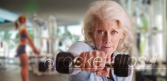 Fit elderly lady at gym working out and looking at camera with determination